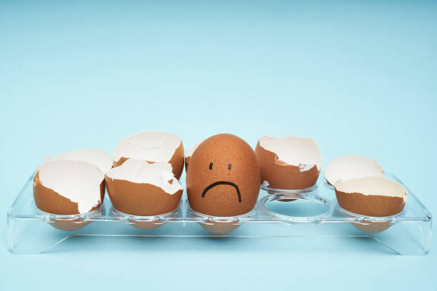 istock Chicken eggs in an egg holder. Full tray of eggs. Half an egg, egg yolk, shell. Emotion and facial expression painted on eggs. 1253169521