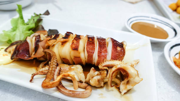 istock Grilled squid in soy sauce on a white plate on the restaurant table 1253182105