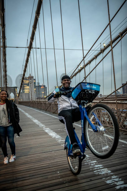 A young man pops a wheelie as he rides a bicycle at dusk across the Brooklyn Bridge in New York City. (March 19, 2020)