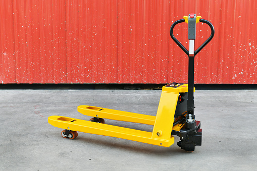 Yellow hand pallet truck in the warehouse front