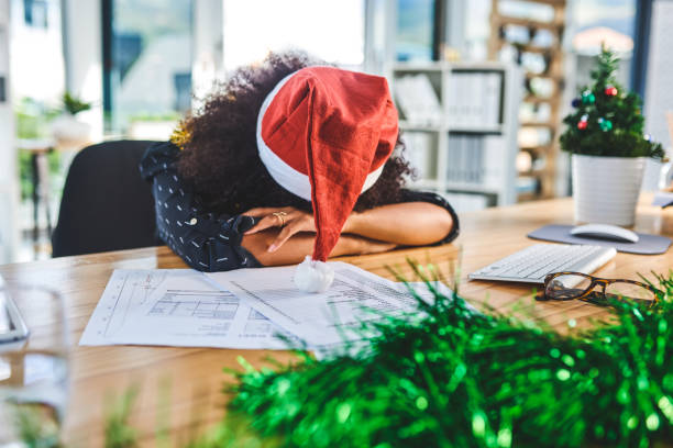I am so tired! Cropped shot of an attractive young businesswoman wearing christmas decorations and sleeping on her desk in the office office christmas party stock pictures, royalty-free photos & images