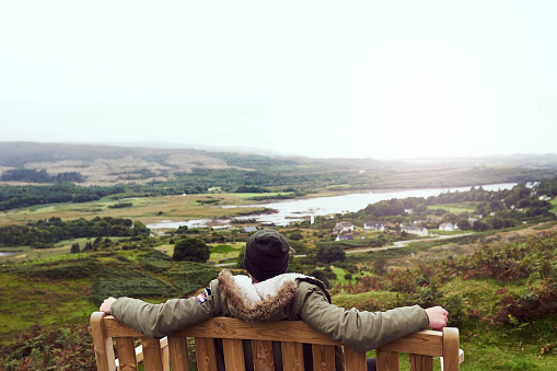 Rearview shot of a man sitting on a bench while admiring a beautiful view