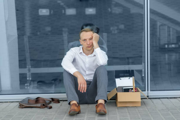 istock A young fired office worker is sitting under his office. Next to him is his stationery. The man is stressed. 1253195530