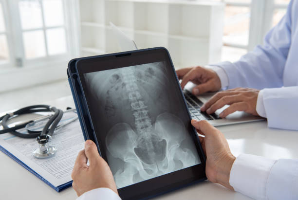 doctor diagnose spine x-ray doctor diagnose spine x-ray image on digital tablet screen with radiologic technologist team. tomography photos stock pictures, royalty-free photos & images