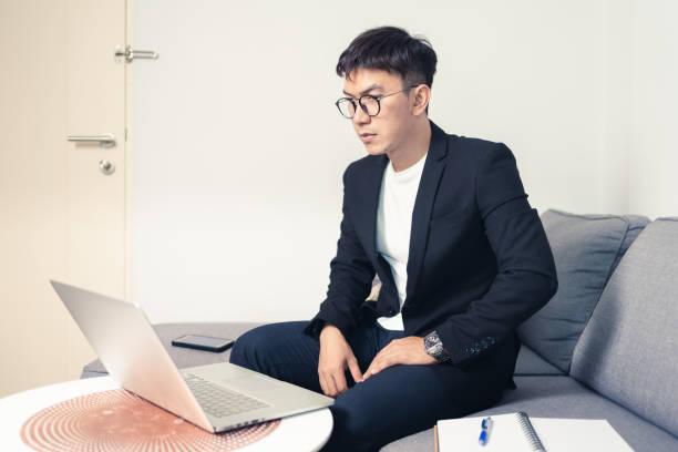 istock Young Asian business man with using laptop computer for video conferencing while working at home. Work from home and Social distancing concept 1253198797