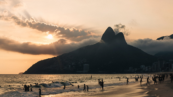 Sunset through the clouds behind the Two Brother Mountain at Ipanema Beach in Rio de Janeiro, Brazil