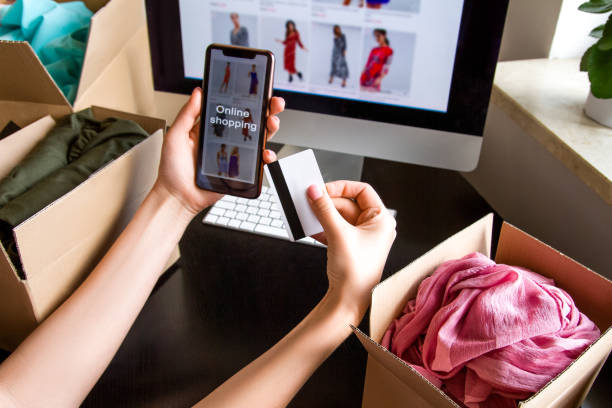 istock Credit card and phone in a hand. Computer screen. boxes, keyboard, mouse. 1253206388