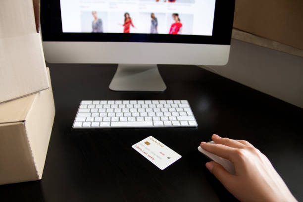 istock Hand with a mouse. Near the keyboard, boxes, computer screen, credit card. 1253206470