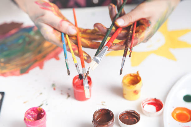 istock Girl whose hands are painted with watercolors. He has brushes in his hands. 1253207548