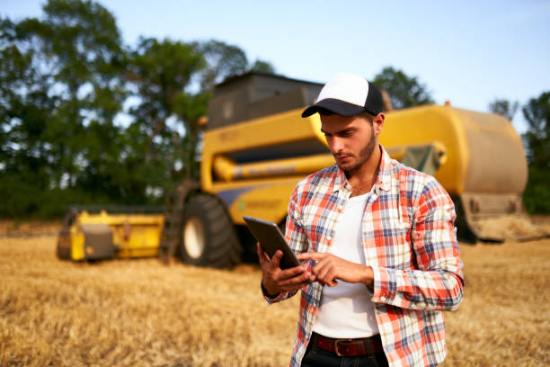 istock Precision farming. Farmer holding tablet for combine harvester guidance and control with modern automation system. Agronomist using online data management software generating yield maps at wheat field 1253210784