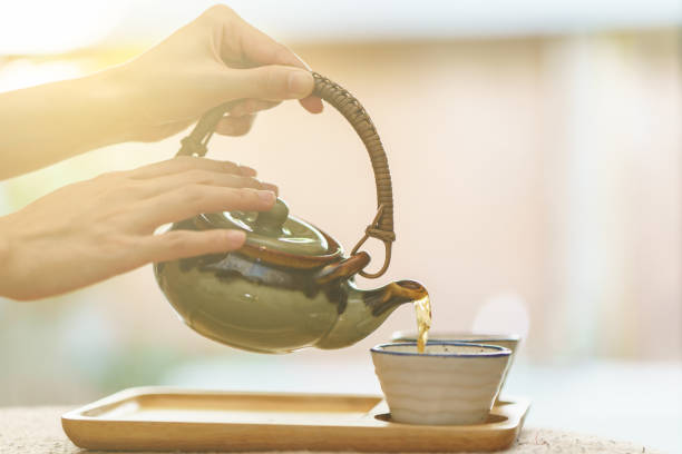 istock hot tea from pot into glass tea cup. 1253212132
