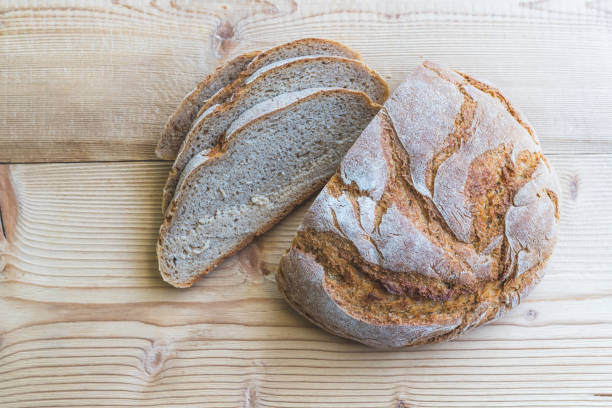 istock Fresh rustic bread in slices on wooden cutting board. 1253212857