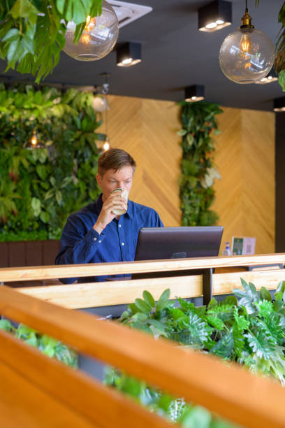 istock Young handsome businessman drinking coffee while using laptop at the coffee shop 1253218310