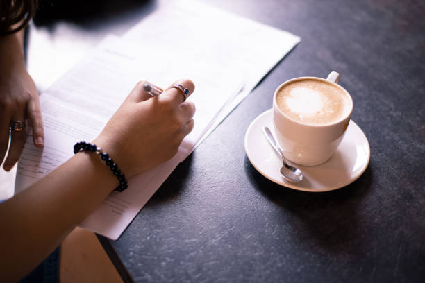 istock model release document writing by woman tender hand in cafe table with cup of coffee office concept 1253222302