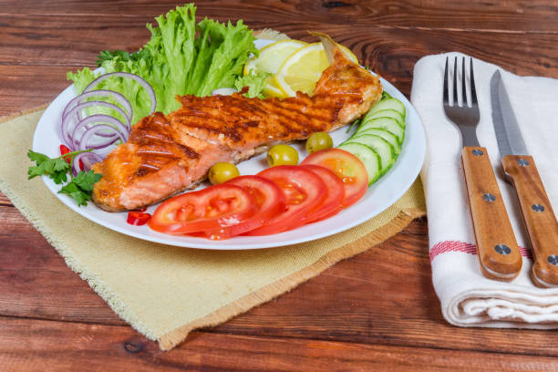 istock Portion of grilled trout fillet with vegetables on rustic table 1253222424