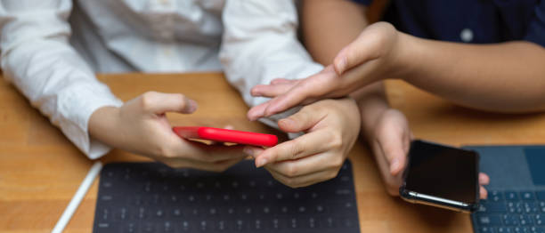 istock Female college students consulting on their project with informations on smartphone while working with tablet 1253222490