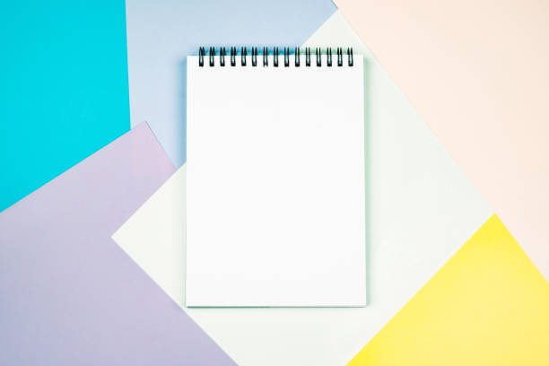 istock Notepad with a blank white sheet on a colorful geometric background. 1253224731