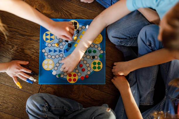 Above view of kids playing ludo game. High angle view of unrecognizable kids playing ludo game at home. board game stock pictures, royalty-free photos & images