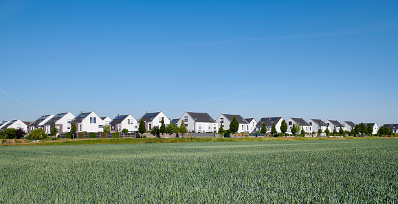Panoramic view of a new settlement, a fresh wheat field in the foreground, Germany.
