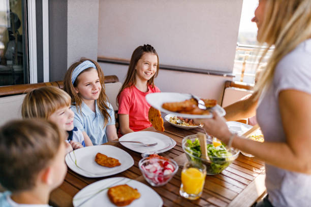 istock Single mother serving lunch to her kids on a terrace. 1253228026