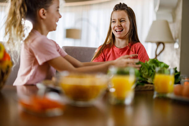 istock Happy sisters talking while preparing vegetables for healthy meal in dining room. 1253228456