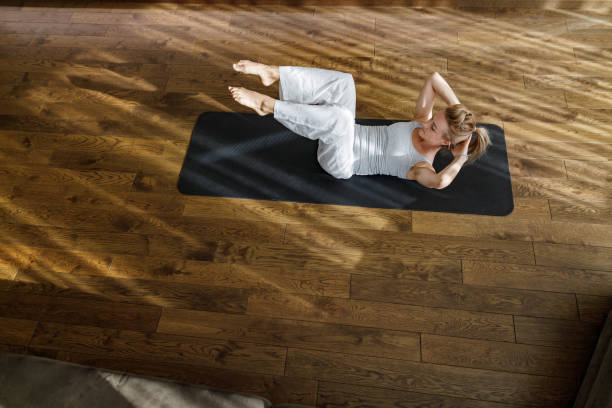 istock Above view of athletic woman doing sit-ups on exercise mat. 1253231567