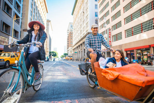 leende familj med ett barn och hund ridning cyklar downtown - parents children cargo bike bildbanksfoton och bilder