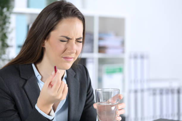 Executive holding painkiller pill and water glass at office Executive holding painkiller pill and water glass at office angry general manager stock pictures, royalty-free photos & images
