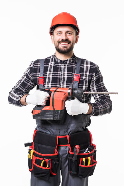 istock Handsome builder in uniform with tool belt holding drill isolated on white background 1253232525