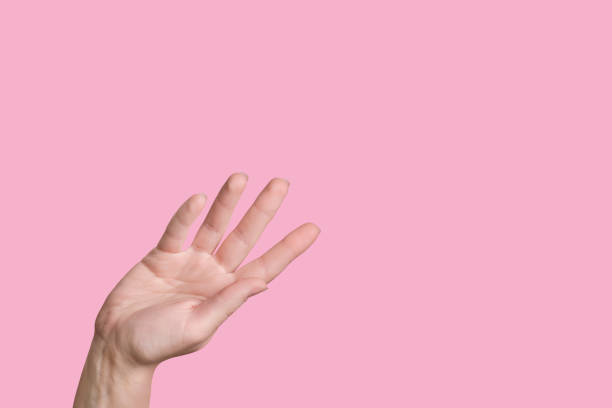 istock Caucasian hand waves while. Farewell gesture. Pink background. 1253232884