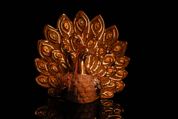 golden peacock statue isolated on dark background.