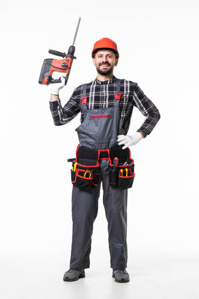 istock Portrait of a manual worker with helmet using a drill tool on white background 1253234361