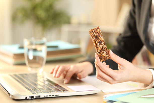 przedsiębiorca ręce gospodarstwa snack bar pracy na laptopie - cookie food snack healthy eating zdjęcia i obrazy z banku zdjęć