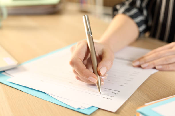 istock Woman hands filling out application form at home 1253235704