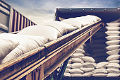 White sugar bags transferred to container for exporting. Forklift handling white sugar bag from warehouse for stuffing into container for export, vintage color.