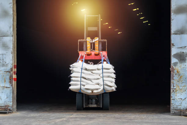 White sugar bags transferred to container for exporting. Forklift handling white sugar bag from warehouse for stuffing into container for export, vintage color. Forklift handling sugar bag for stuffing into container for exportWhite sugar bags transferred to container for exporting. Forklift handling white sugar bag from warehouse for stuffing into container for export, vintage color. silo bag stock pictures, royalty-free photos & images