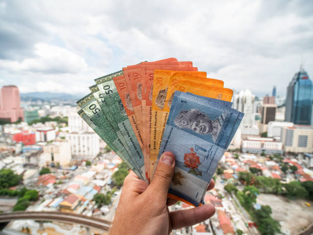 un giovane tiene in mano i soldi della malesia sullo sfondo del centro della città di kuala lumpur - malaysian ringgit foto e immagini stock