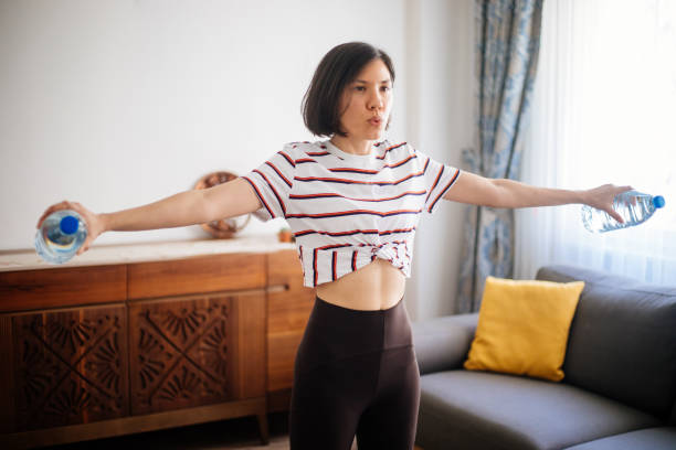istock Woman workout at home with water bottles 1253236646