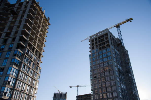 istock Tower crane working at construction site on blue sky background with white clouds. Construction process of the new residential buildings. Installing double glazed windows 1253237372
