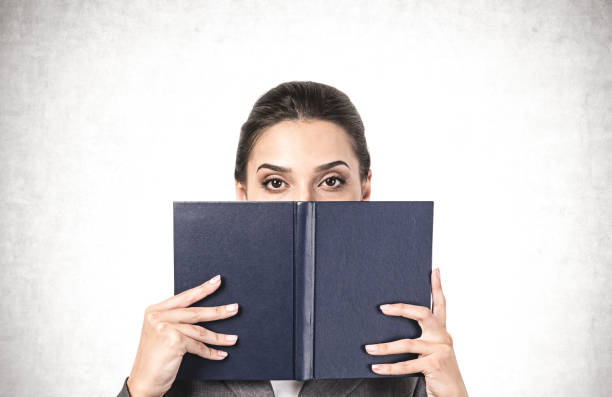 istock Woman covering her face with book 1253238178