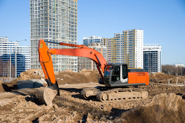 Excavator during earthmoving at construction site. Backhoe digg ground at construction site for the construction of the road and laying sewer pipes district heating. Earth-moving heavy equipment excavadora durante el movimiento de tierras en el sitio de construcción. terreno de digg retroexcavadora en el sitio de construcción para la construcción de la carretera y la colocación de tuberías de alcantarillado calefacción urbana. equipo pesado