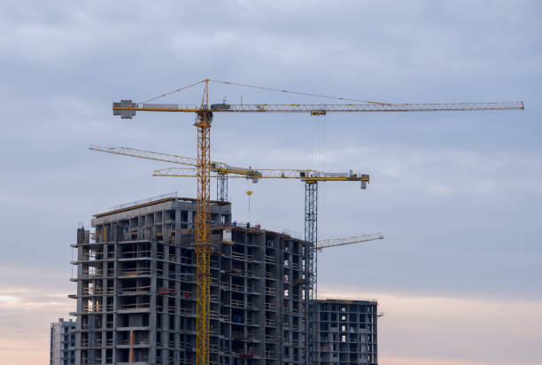 istock Tower cranes working at construction site against blue sky. Crane lifting a concrete bucket. Construction process of the new residential buildings. Transportation blocks and pouring of the cement mix 1253238487