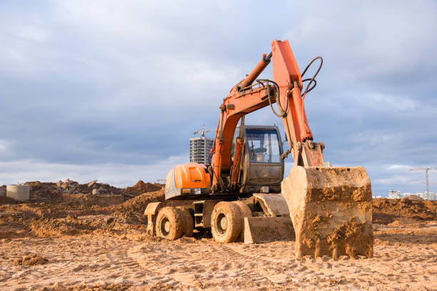 istock Bucked wheel excavator digs ground at a construction site for installing concrete storm pipes. Backhoe the digging pipeline ditch. Commercial and Public Civil Work Contracting, trenching, tamps soil 1253239334