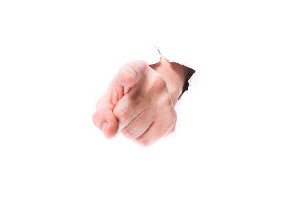 istock male hand showing finger through a hole in paper on a white background isolate. close up, copy space. 1253240880