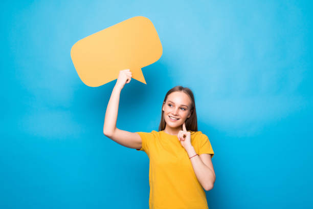 istock Young woman holding a speech bubble isolated on a blue background 1253243893