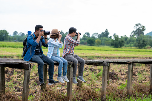A group of male and female fellow travelers sat on a wooden bridge and held a camera taking pictures.