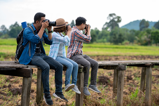 A group of male and female fellow travelers sat on a wooden bridge and held a camera taking pictures.