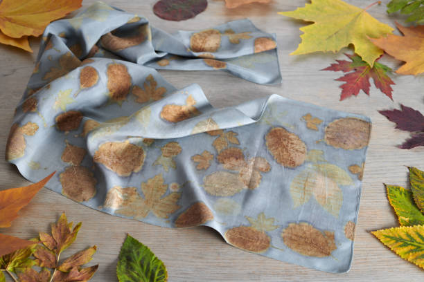 istock Hand-dyed silk scarf surrounded by autumn leaves. Eco-print technique 1253245082