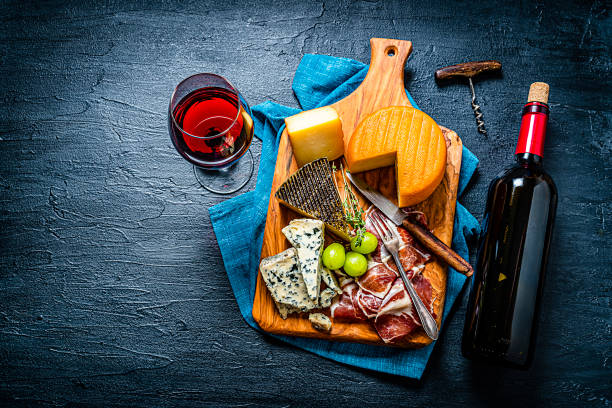 istock Appetizer backgrounds: cheeses, Serrano ham and red wine on dark table. Copy space 1253245511