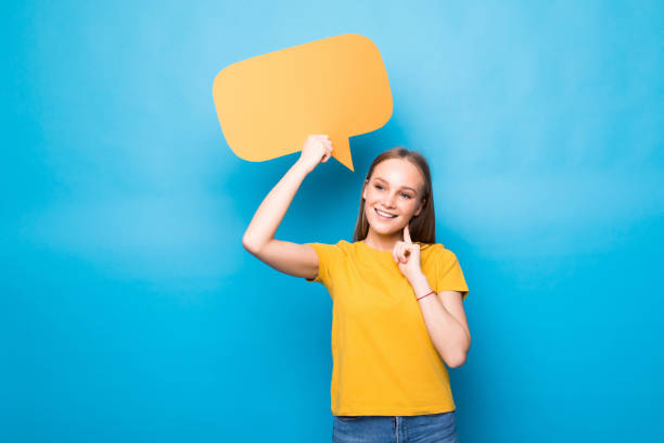 istock Young woman holding a speech bubble isolated on a blue background 1253246360
